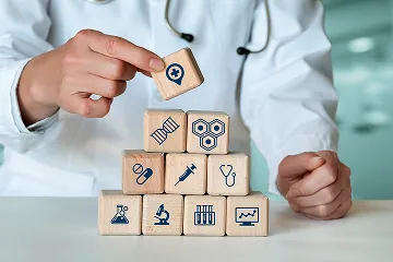 Hands stacking building blocks with medical icons