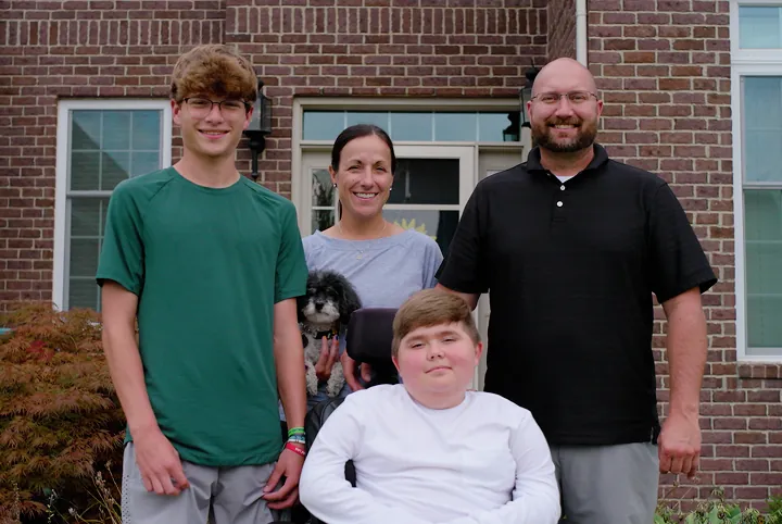 Nathan with his family standing together outside their home